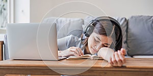 Tired teenage asian female student fell asleep at her desk, resting her head on her hand, during a lecture in home