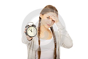 Tired teenage woman with alarmclock.