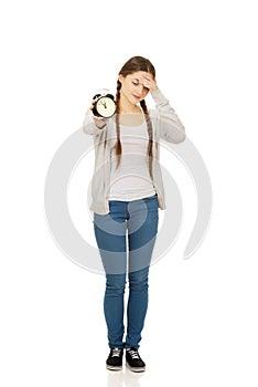 Tired teenage woman with alarmclock. photo