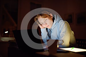 Tired teenager napping while studying at home with laptop and tablet pc at night. Online learning, distance lessons, freelance -