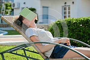 Tired teenager student asleep on sunbed with book