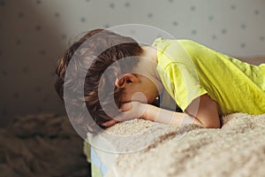 Tired toddler boy lying on the bed with his face down. Crying little kid