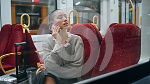 Tired tourist calling mobile phone in train. Short hair woman talking smartphone