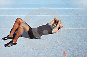 Tired track athlete lying down and feeling exhausted. Active, fit, competitive runner suffering from burnout, heatstroke