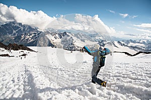 The tired traveler descends from the snowy top against the background of snow-capped mountains