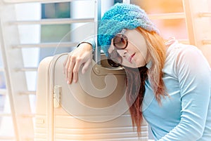 Tired traveller tourist woman sleeping on luggage while waiting