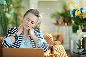 Tired trendy female having neck pain with laptop