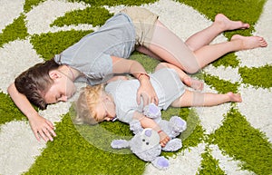 Tired two girls sister fell asleep on the carpet