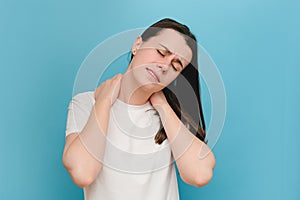 Tired unhappy sad young female suffering neck ache injury, touching neck with hand, muscular pain, massaging sore shoulders after