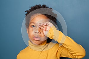 Tired unhappy small black child boy crying up on blue background