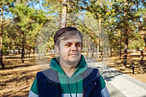 Tired and unhealthy european caucasian white young male man in autumn Park or forest. Serious concerned Headshot man lifestyle