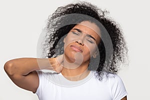 Tired upset african woman massaging stiff neck isolated on background photo