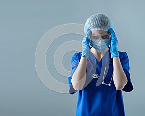 Tired, upset and depressed medical worker in protection suit. Nurse, surgeon, doctor or paramedic in blue uniform