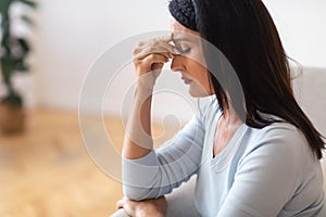 Tired upset middle-aged older woman massaging nose bridge