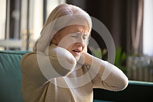 Tired upset old senior woman feeling stiff neck pain concept