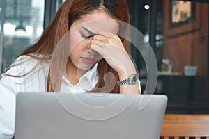 Tired upset young Asian business woman suffering from severe from depression in workplace.