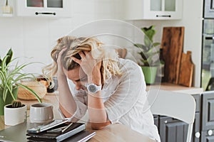 tired, upset young woman with laptop working at home in the kitchen