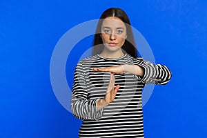 Tired upset young woman showing time out gesture, limit or stop sign, bored of work, take a break