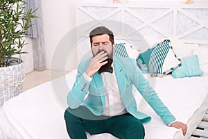 Tired of waiting. Elegant man yawn sitting on bed. Bearded man in classy style. Fashion look of groom. Wedding man