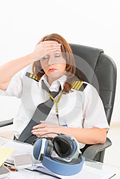 Tired woman airline pilot in the office