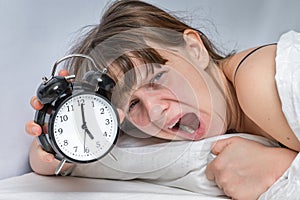 Tired woman with alarm clock does not want waking up