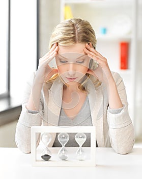 Tired woman behind the table with hourgalss