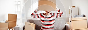 Tired woman with cardboard box on her head sitting on the sofa in her new house.