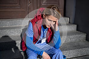 Tired woman caregiver, nurse or healthcare worker sitting outdoors on the way to work.