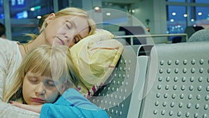 Tired woman with a child sleep in the airport terminal. Delay or cancellation of voyage concept