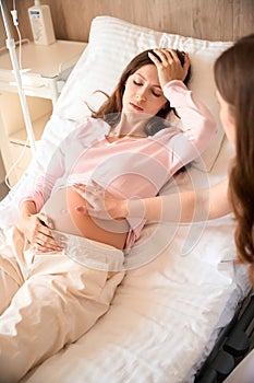 Tired woman with contractions laying in bed with IV drip