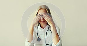 Tired woman doctor working with documents while sitting at desk in medical clinic office