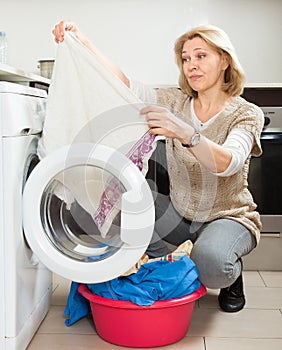 Tired woman doing laundry with washing machine