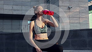 Tired Woman drink water red bottle after morning workout