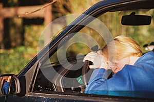 Tired woman driving a car. A middle-aged woman in her forties leaned over the steering wheel of a car. Fatigue, exhaustion, rest