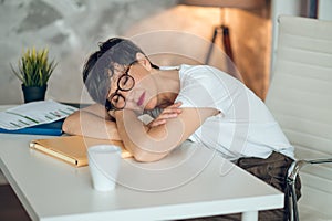 Tired woman in eyeglases napping at the table in the office