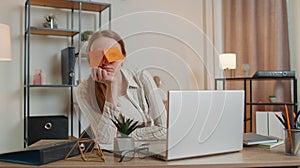 Tired woman teacher using laptop computer with funny stickers on eyes sleeps at workplace, napping