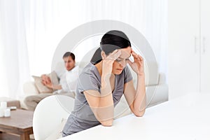 Tired woman having a headache sitting at a table