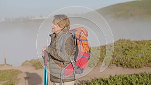 Tired woman hiking on mountains with trekking poles