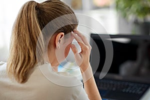 tired woman with laptop having headache at office