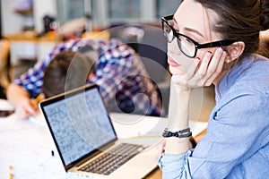 Tired woman with laptop sitting in meeting room