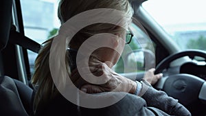 Tired woman massaging numb neck sitting on driver seat of car, back-view