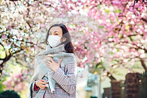 Tired woman in medical mask walking in spring.Woman hope in overcoming coronavirus epidemic