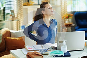 Tired woman in modern house in sunny day having back pain