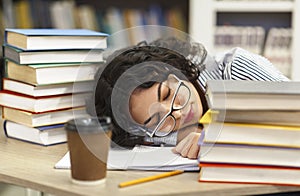 Tired woman napping on books stack in library