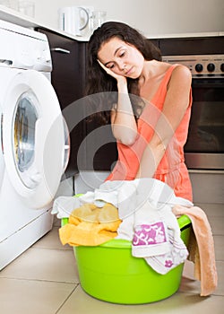 Tired woman near washing machine