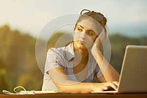 Tired woman outdoors with laptop yearns for break