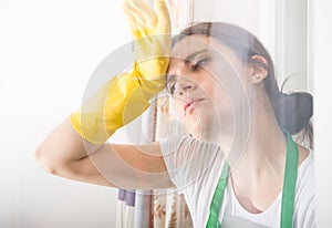 Tired woman with protective gloves wiping her forehead
