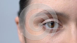 Tired woman with red blood vessels in eyes slowly blinking looking into camera