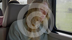 a tired woman, a refugee from Ukraine, is resting on a train. Face close up. slow motion
