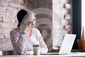 Tired woman ropps his head with his hand at office